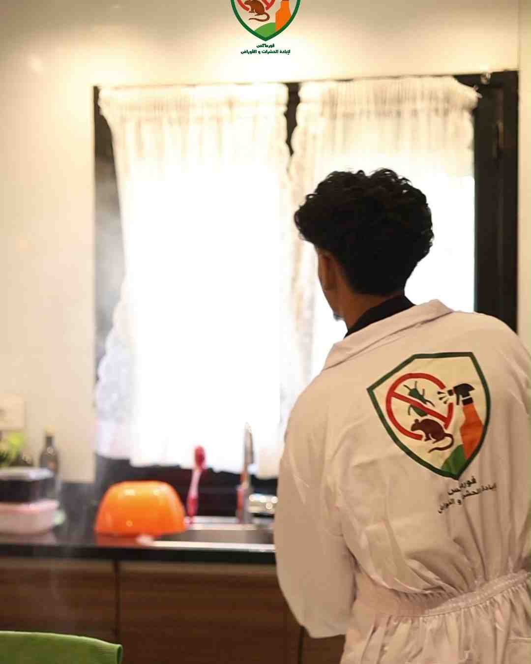 A Formax technician in uniform with the company logo on his back, treating a kitchen