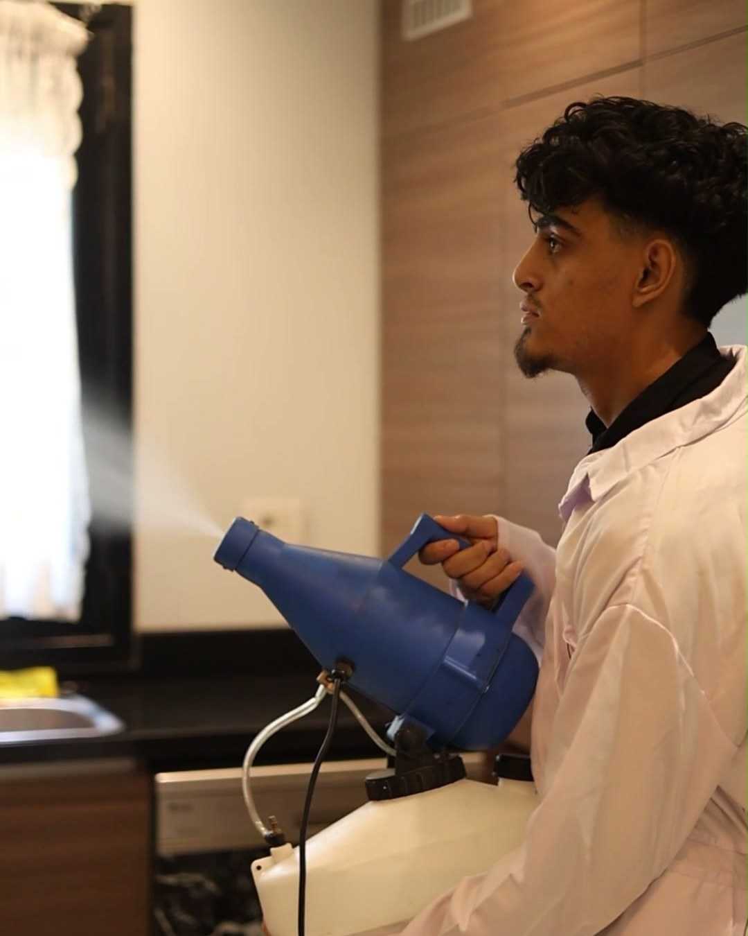 The technician treating the kitchen with a fogging sprayer.